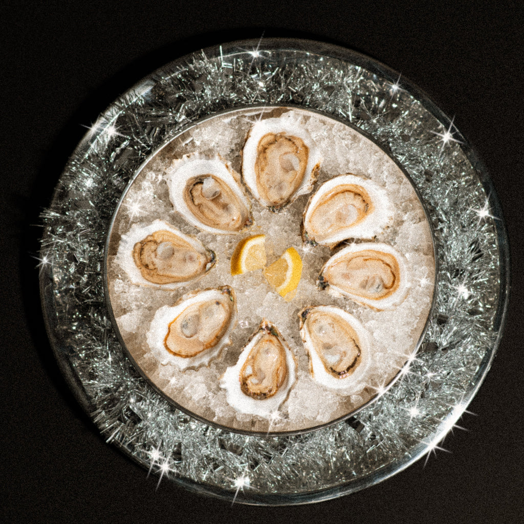 Oysters on a bed of ice with lemon wedges on a dark background